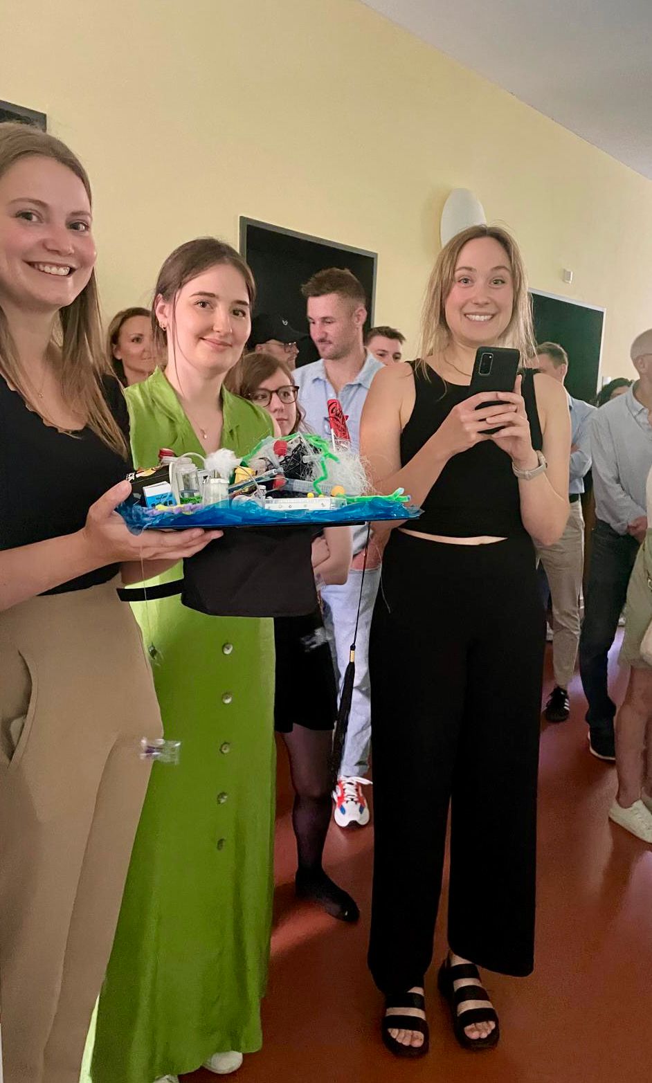 Im Vordergrund: drei Doktorandinen mit dem Doktorhut, im Hintergrund Kollegen und Gäste