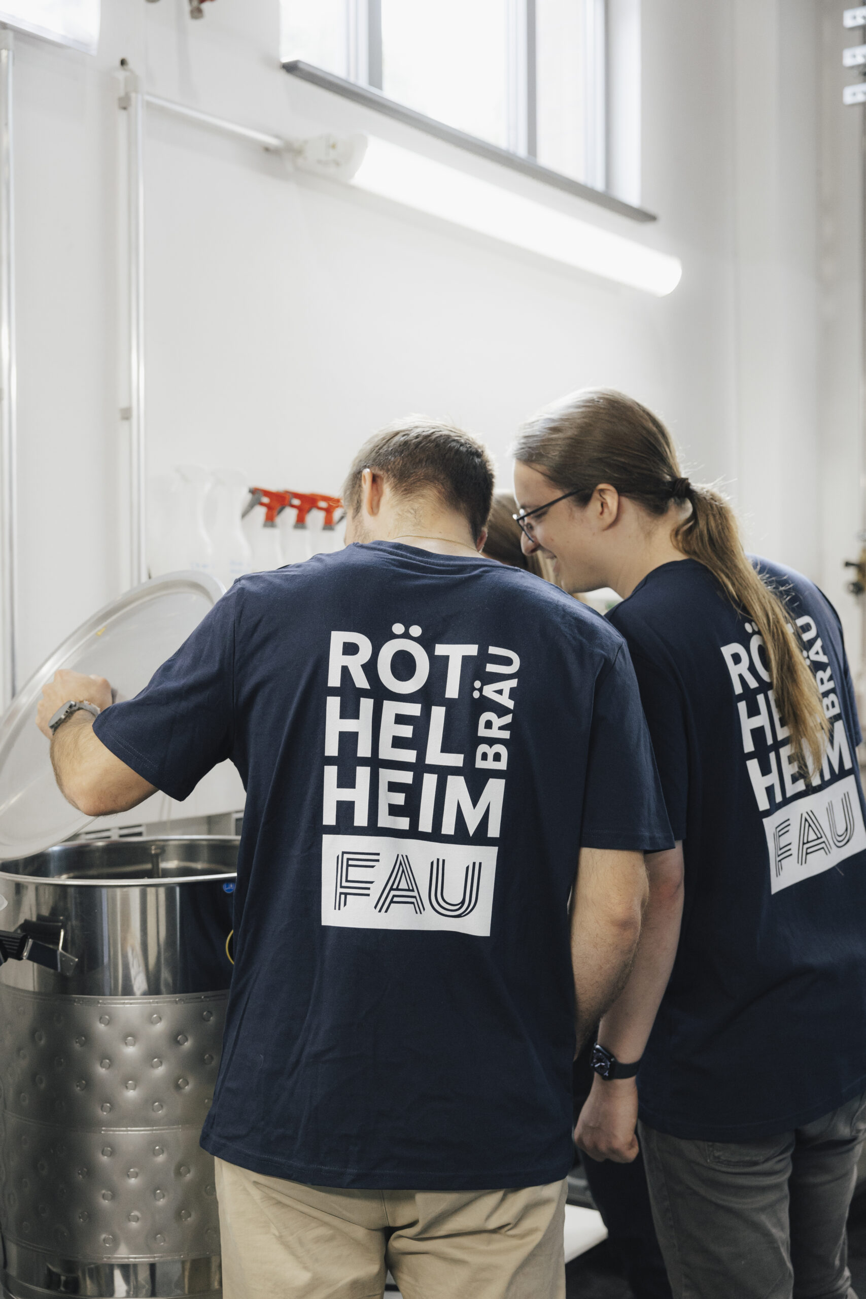 Zwei männliche Mitglieder des Brauerei-Tams über einem Braukessel