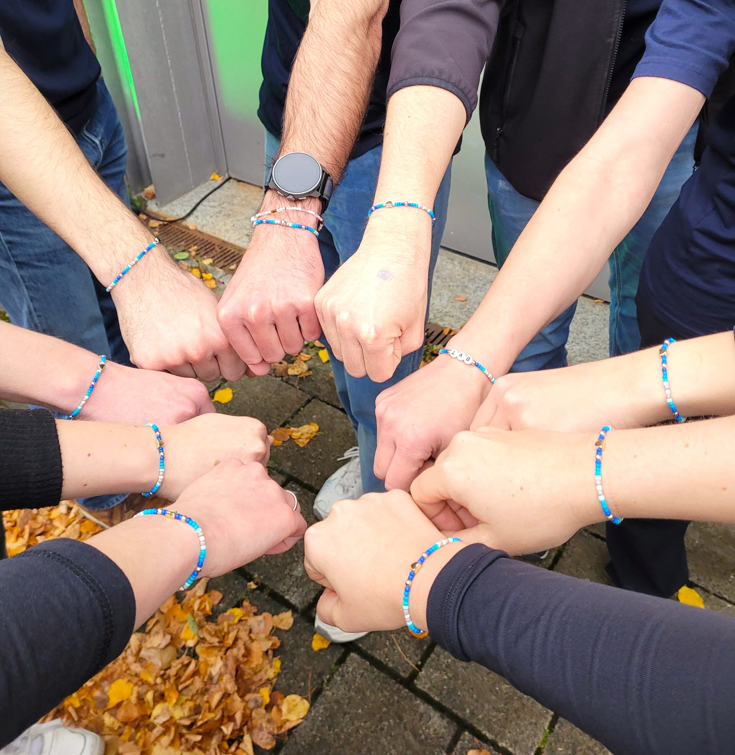 10 Hände mit gleichen Armbänder die einen Kreiß formen