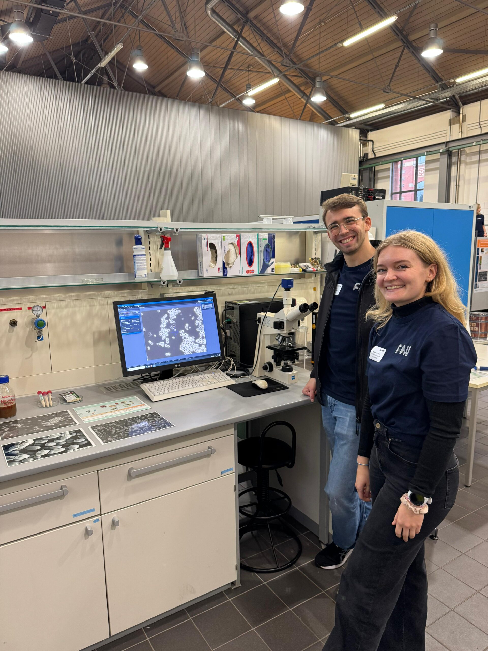 Zwei Personen: Maike (weiblich) und Matthias (männlich) vor der Hefe-Beobachtung (unter Mikroskop) Station